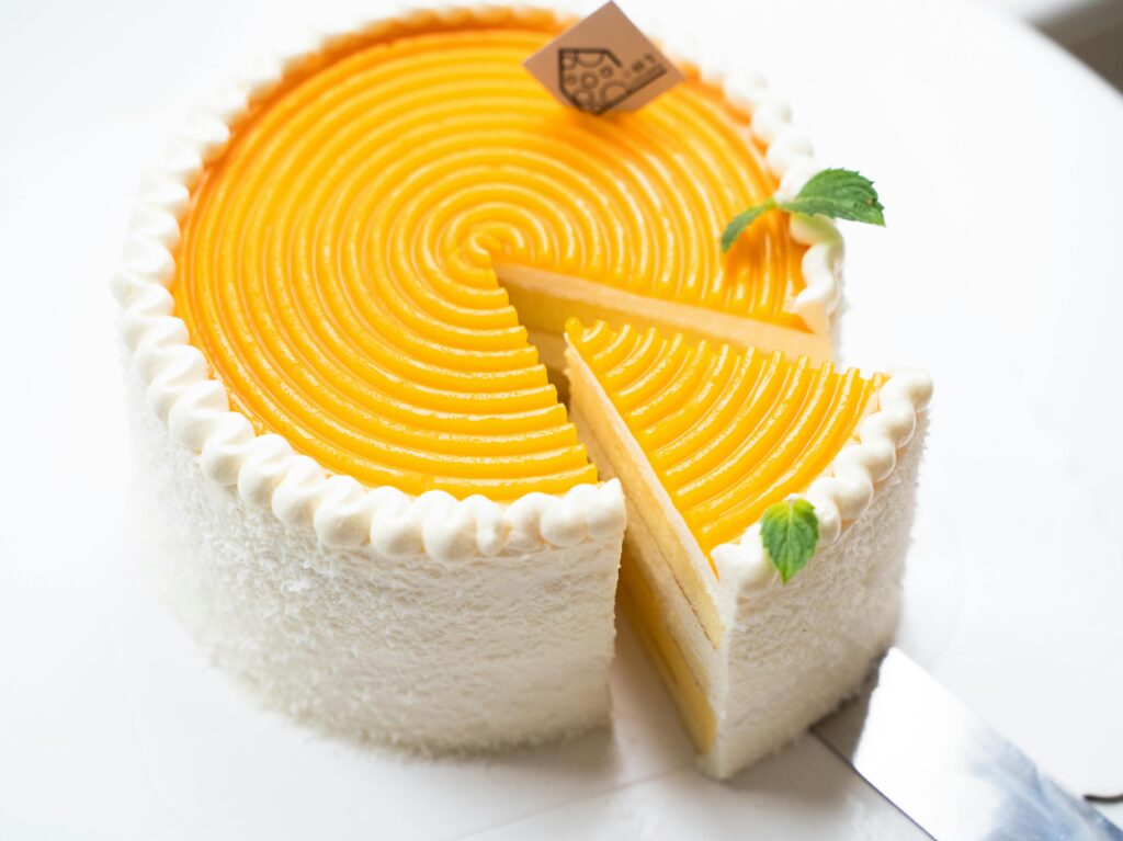 Sliced mango cake with creamy texture and fresh mint, perfect for dessert lovers.